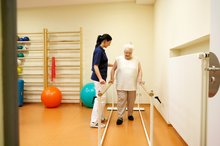 Physiotherapeutin übt mit einer älteren Dame