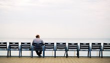 Mann sitzt alleine auf einer Bank