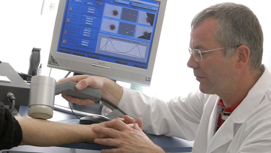 Prof. von den Driesch untersucht die Haut am Unterarm eines Patienten