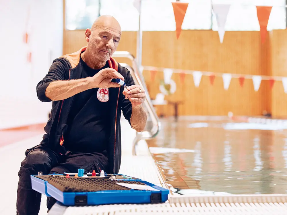 Mann entnimmt Wasserprobe im Schwimmbad